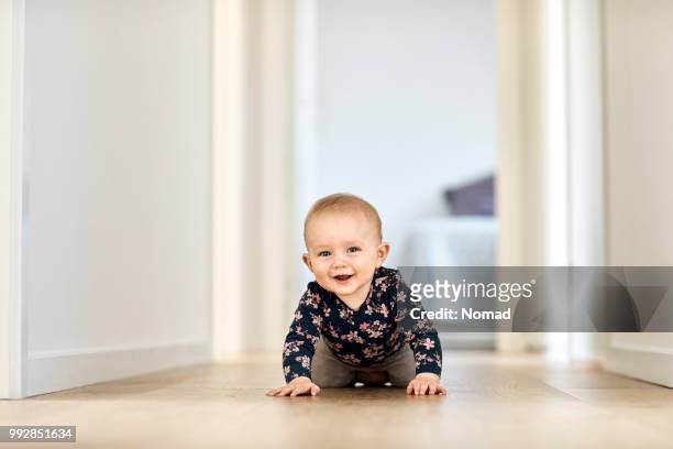 bambino sorridente che striscia nel corridoio di casa - camminare a gattoni foto e immagini stock