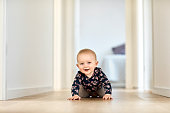Smiling baby boy crawling in corridor at home