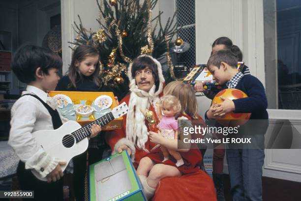 Le chanteur Antoine déguisé en Père Noël avec des enfants autour d'un sapin, circa 1970, France.