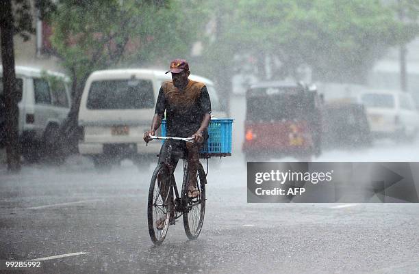 Sri Lankan man rides a bicycle through heavy rain on a street in Colombo on May 14, 2010. The capital city was lashed by heavy rains causing majot...