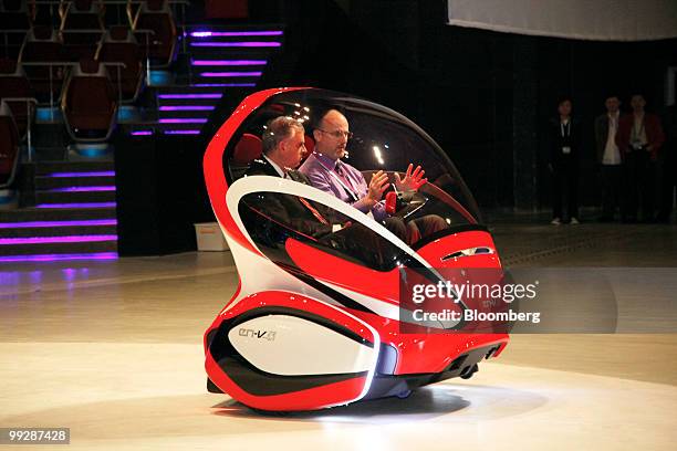 Secretary of Transportation Ray LaHood, left, rides in a General Motors Co. En-V concept vehicle at the World Expo's SAIC-GM Pavilion in Shanghai,...