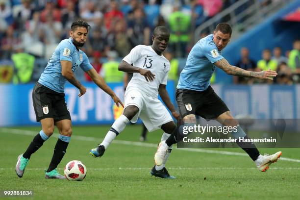 Ngolo Kante of France is tackled by Jonathan Urretaviscaya and Jose Gimenez of Uruguay during the 2018 FIFA World Cup Russia Quarter Final match...