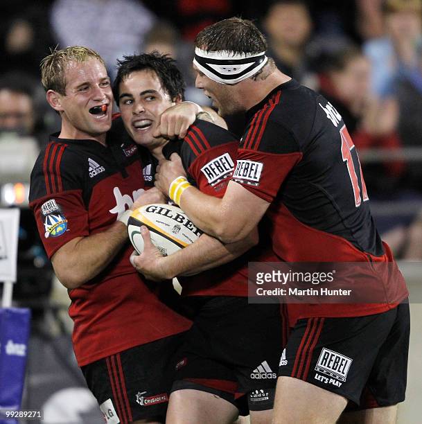 Zac Guildford of the Crusaders is hugged by team mates Andy Ellis and Wyatt Crockett after scoring a try during the round 14 Super 14 match between...