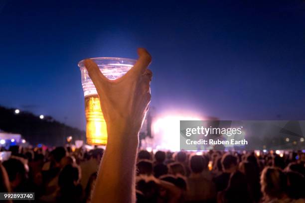 having fun in a music concert rising the hand with a beer - hand back lit stock pictures, royalty-free photos & images