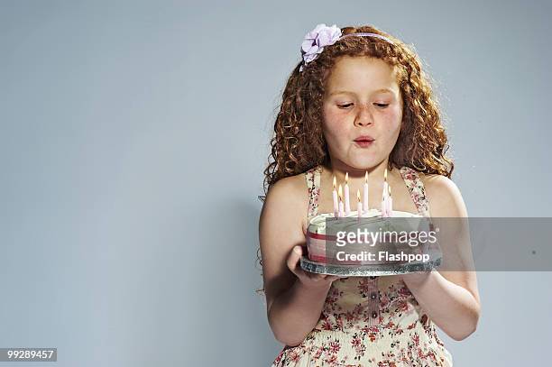 portrait of girl blowing out candles on cake - somente crianças - fotografias e filmes do acervo