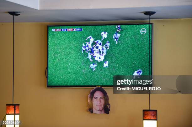 Picture of Uruguayan forward Edinson Cavani, hangs from a TV during the broadcasting of the Russia 2018 FIFA World Cup football match, Uruguay...