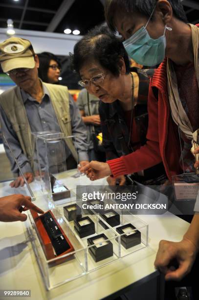 Potential customers look at diamonds produced from the ashes of the deceased during the Asia Funeral Expo in Hong Kong on May 14, 2010. The diamonds...