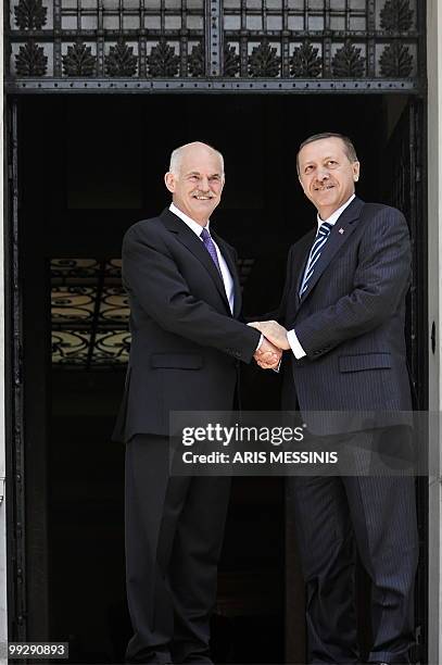 Greek Premier George Papandreou holds the hand of his Turkish counterpart Recep Tayyip Erdogan before their meeting in Athens on May 14, 2010....