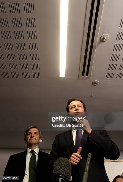 British Prime Minister David Cameron speaks next to Chris Huhne, the Secretary of State for Energy and Climate Change, during address to Department...