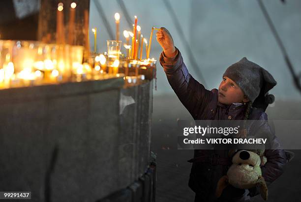 Little girl lights a candle at the monument of the dead miners remembrance in the town of Mezhdurechensk, Kemerovo region of Western Siberia late on...