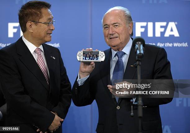 President Sepp Blatter displays an electronic device with a picture of people smiling beside President of The Japan Football Association and Chairman...