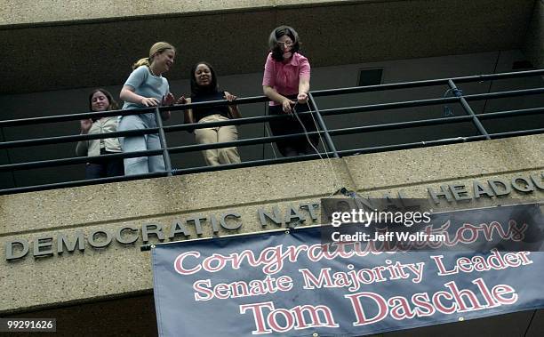 Alexandra Acker lowers a banner which congratulates Senator Tom Daschle, D-SD, with the help of her coworkers Tiffany Miller and Molly Stoff at the...