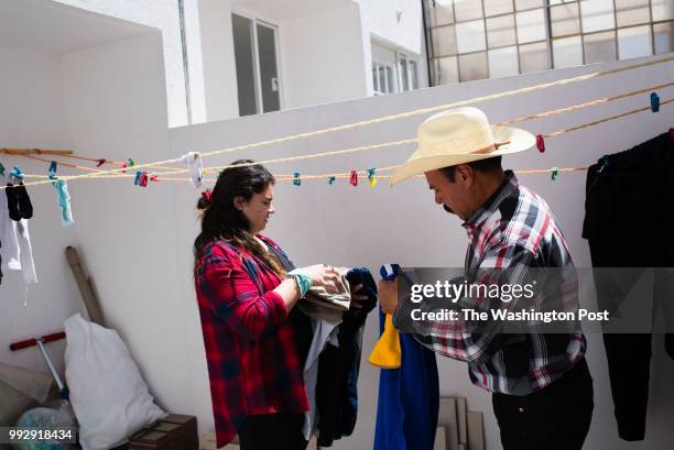 Lourdes Quintana-Salazar takes laundry off the line with her father, Luis Quintana in the backyard of the house in Toluca, Mexico, which was...