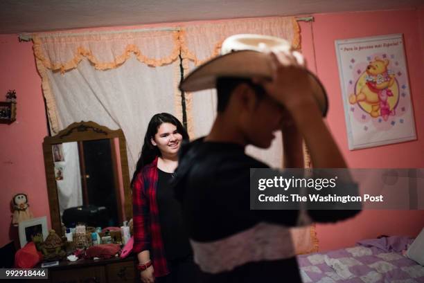Lourdes Quintana-Salazar, 16 watches her younger brother, Bryan, try on a hat given to him by his grandmother during their their visit to their...