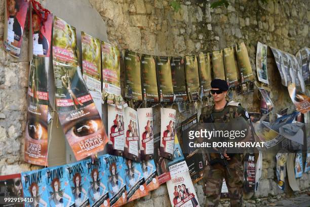 French soldier walks past posters advertising plays as he patrols in a street of Avignon, southeastern France on July 6, 2018 on the first day of the...