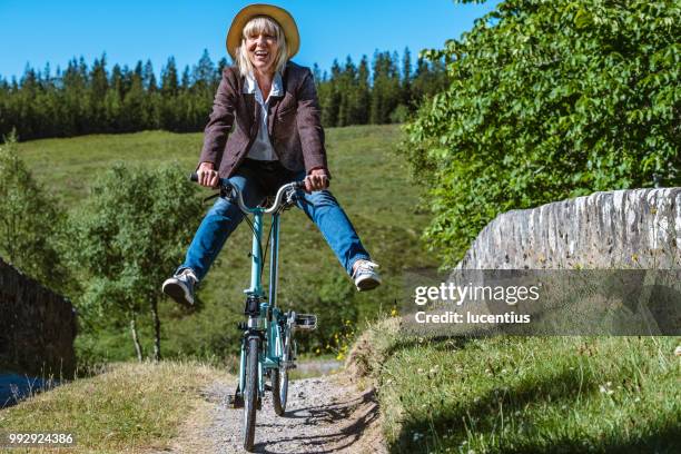haute femme avoir du plaisir sur le vélo pliant - vélo pieds en l'air photos et images de collection