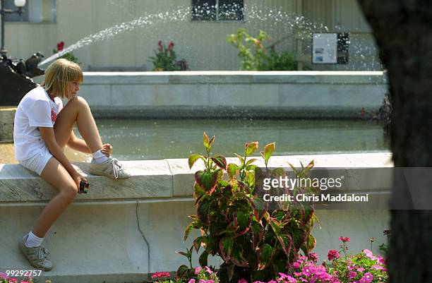Kristen Maslowski visiting from Chicago, sits on the fountain of Bartholdi Park.