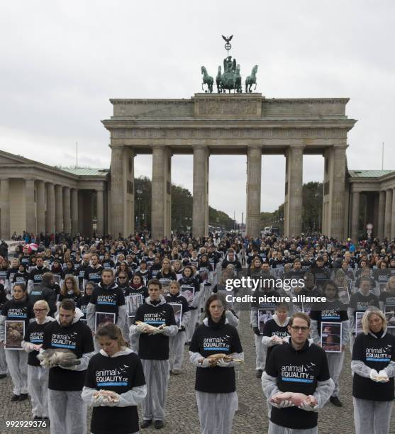 Animal rights activists from the group Animal Equality hold dead animals in their hands during a silent protest in front of the Brandenburg Gate in...