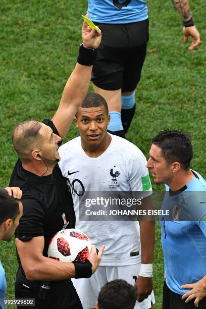 Argentine referee Nestor Pitana presents Uruguay's midfielder Cristian Rodriguez with a yellow card during the Russia 2018 World Cup quarter-final...
