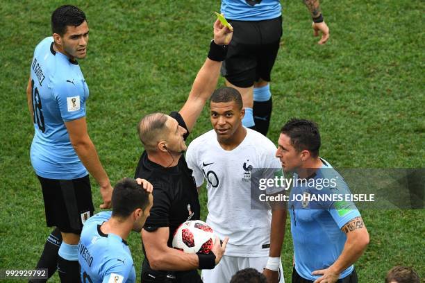 Argentine referee Nestor Pitana presents Uruguay's midfielder Cristian Rodriguez with a yellow card during the Russia 2018 World Cup quarter-final...