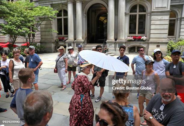 Tour guide Margaret Ann Brady keeps cool with a parasol on a hot day as she leads a tour at the front courtyard of Old Boston City Hall on July 3,...