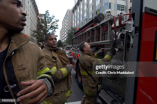 Firefighters Ricardo Kingsbury, James Christian, and Lt. Terry Williams put the hose away after putting out a trash can fire on 7th St.