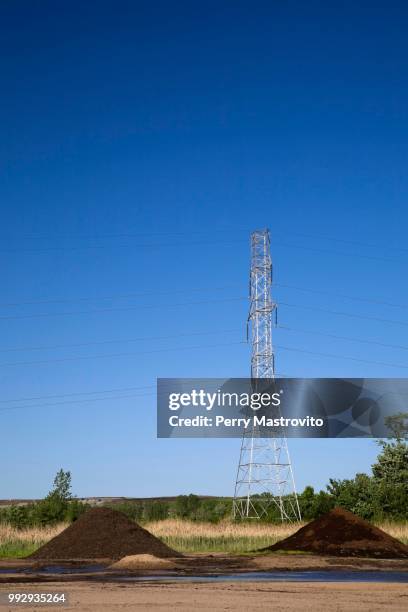 mounds of topsoil and a hydro electricity transmission tower in a commercial sandpit, quebec, canada - hydro stock-fotos und bilder