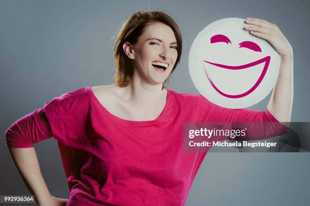 smiling young woman holding a smiley face - smiley face stock pictures, royalty-free photos & images