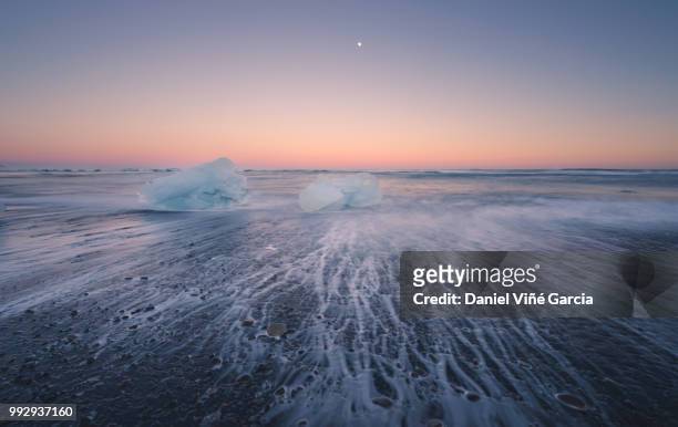 icebergs floating on icy beach at sunset, south iceland - south east iceland stock pictures, royalty-free photos & images