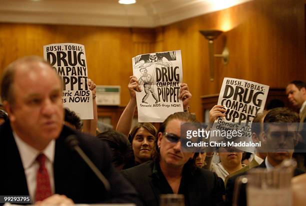 Demonstrators from HealthGap hold up signs promoting generic Aids medication during Randall Tobias, global HIV/AIDS coordinator testimony at a Senate...