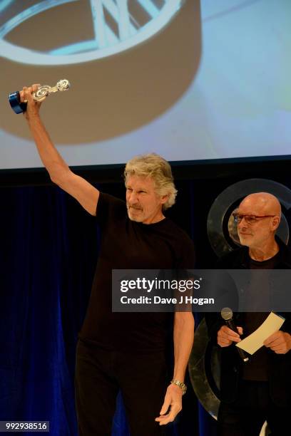 Roger Waters , winner of the O2 Silver Clef Award and presenter Brian Eno on stage during the Nordoff Robbins' O2 Silver Clef Awards ceremony at...