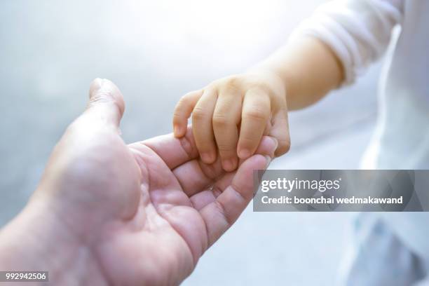 holding baby hand - adoption photos et images de collection