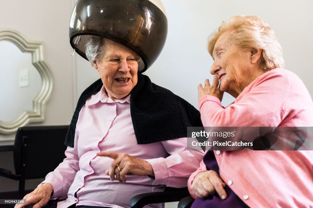 Two senior women at the hair dresser sharing a laugh together