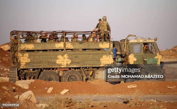 Syrian government soldiers ride in an army truck near the Nassib border crossing with Jordan in the southern province of Daraa on July 6 after they...