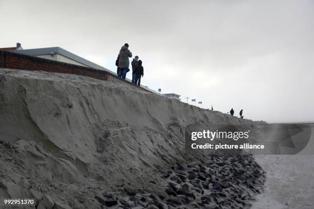 People stand on the break-off edge of the beach on Wangerooge island, Germany, 29 October 2017. Due to storm 'Herwart', a part of the lower...