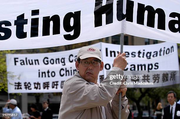 Chinese immigrant Qi Han holds a banner at a Falun Gong rally to call for "an immediate opening of all labor camps in China for international...