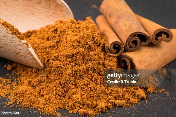 cinnamon sticks with powder on dark stone plate - cinnamon bark stock pictures, royalty-free photos & images