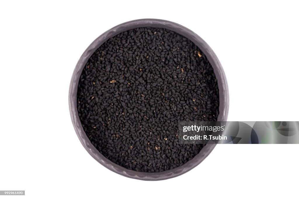 Sesame black seeds in stone bowl isolated on white background