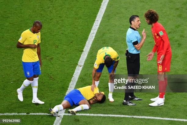 Serbian referee Milorad Mazic talks to Belgium's midfielder Marouane Fellaini as Brazil's forward Neymar lies on the ground during the Russia 2018...