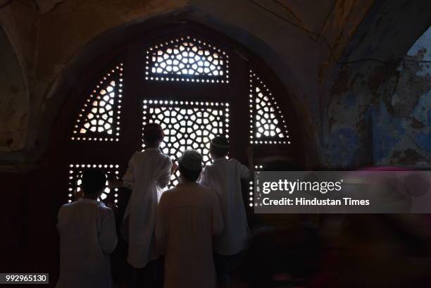 Man and kids peer through the perforated stone window or latticed screen at the shrine of Sufi saint Hazrat Syed Muhammad Nizamuddin Auliya at the...