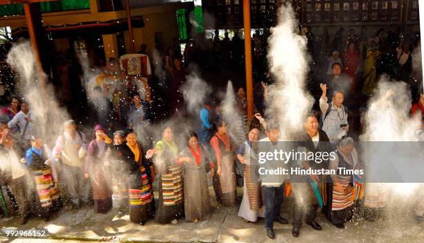 Exile Tibetans throw white flour powder in air during the long life prayers on the occasion of 83rd birthday of Tibetan spiritual leader, Dalai Lama...