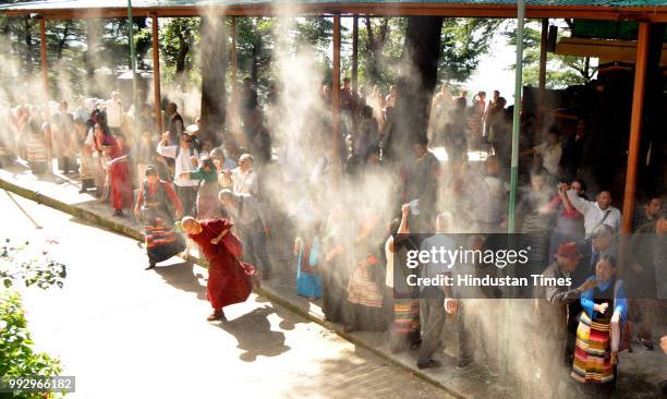 Exile Tibetans throw white flour powder in air during the long life prayers on the occasion of 83rd birthday of Tibetan spiritual leader, Dalai Lama...