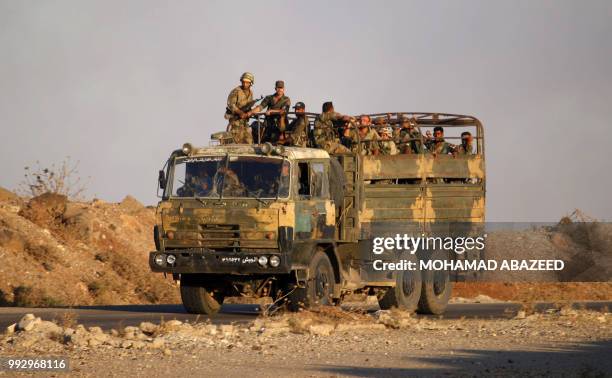 Syrian government soldiers ride in an army truck near the Nassib border crossing with Jordan in the southern province of Daraa on July 6 after they...