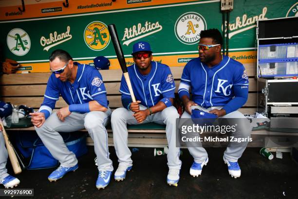Paulo Orlando, Alcides Escobar and Abraham Almonte of the Kansas City Royals sit in the dugout prior to the game against the Oakland Athletics at the...