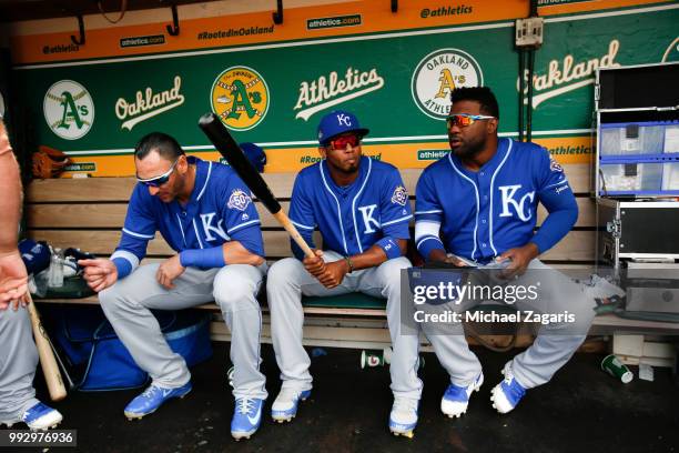 Paulo Orlando, Alcides Escobar and Abraham Almonte of the Kansas City Royals sit in the dugout prior to the game against the Oakland Athletics at the...