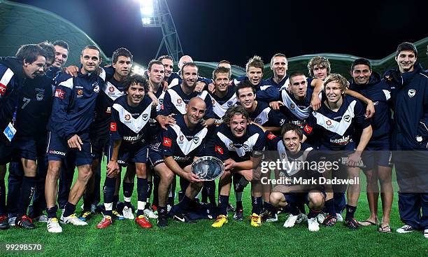 Kevin Muscat of the Victory holding a momento from the club poses for a team photo at the completion of the Kevin Muscat Testimonial match between...