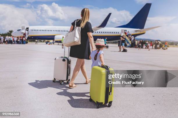 mutter und tochter mit ihrem gepäck einsteigen in ein flugzeug - boarding plane stock-fotos und bilder