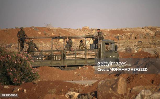 Syrian government soldiers ride in an army truck near the Nassib border crossing with Jordan in the southern province of Daraa on July 6 after they...