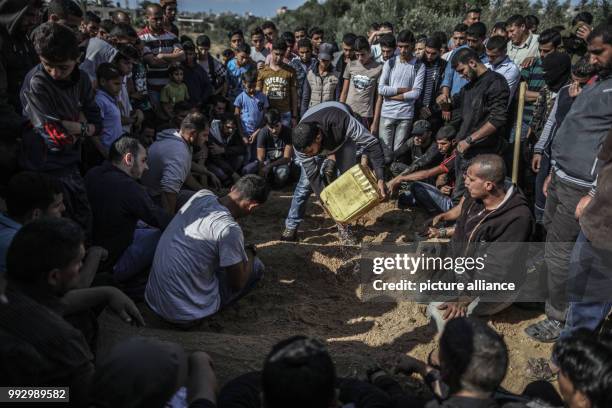 Dpatop - Mourners sprinkle water on the grave of a militant, who killed in an Israeli operation to blow up a tunnel stretching from the Gaza Strip...
