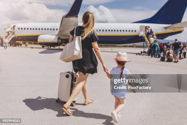 madre e figlia che si tengono per mano mentre salgono su un aereo - imbarcarsi foto e immagini stock